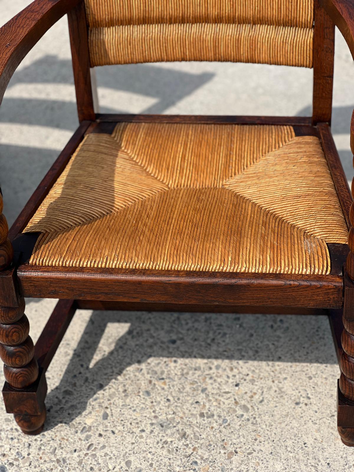 Fauteuil en chêne teinté et paille, travail français 1950