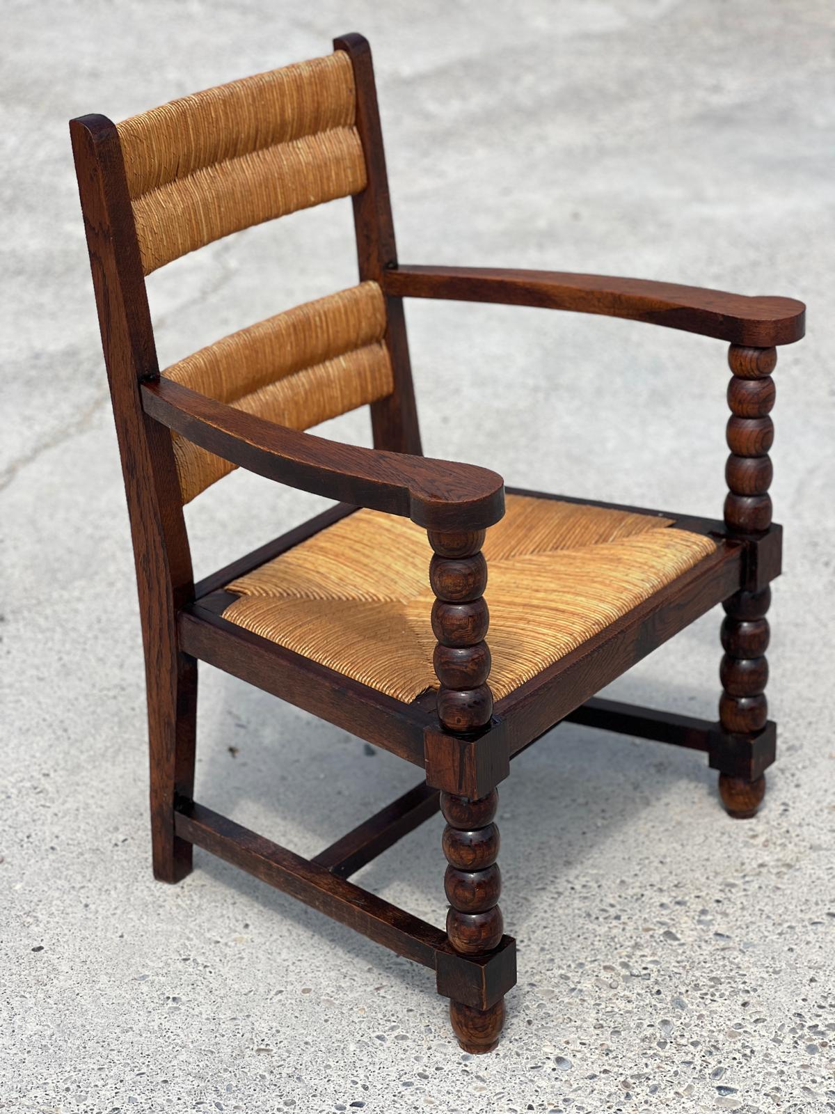 Fauteuil en chêne teinté et paille, travail français 1950