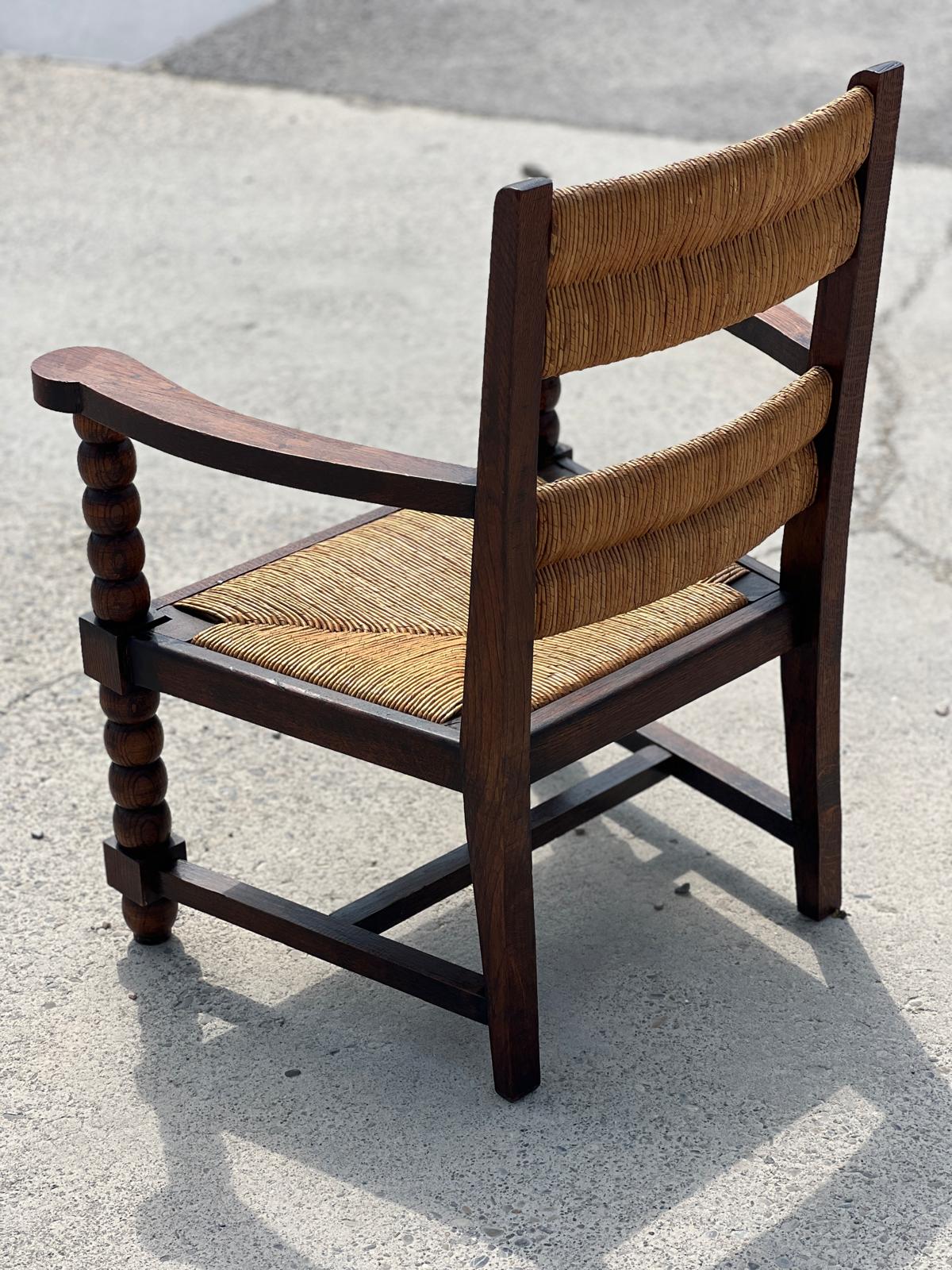 Fauteuil en chêne teinté et paille, travail français 1950